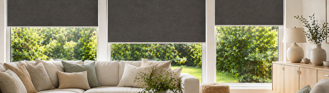 Yaringa textured blackout roller blinds in charcoal grey installed in a modern New Zealand living room, featuring large windows, soft natural light, and contemporary neutral interior styling. Yaringa textured blackout roller blinds in charcoal grey installed in a modern New Zealand living room, featuring large windows, soft natural light, and contemporary neutral interior styling.
